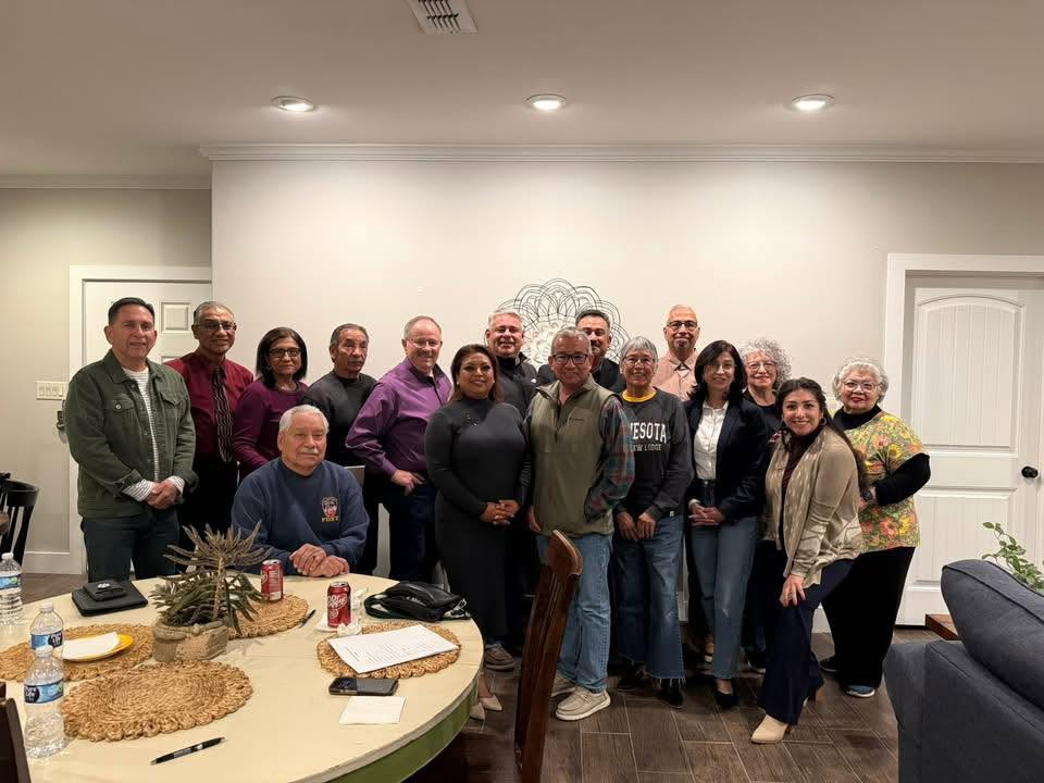A group of people gathered together indoors, smiling for a photo.